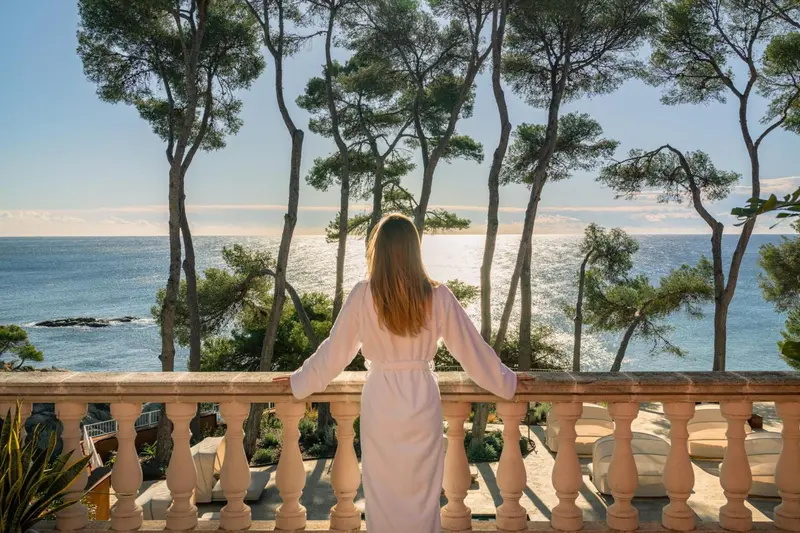 Une personne se tient sur une terrasse en admirant la vue sur la mer.