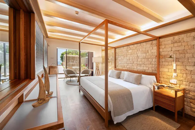 Une chambre lumineuse avec un lit à baldaquin et un mur en pierre.