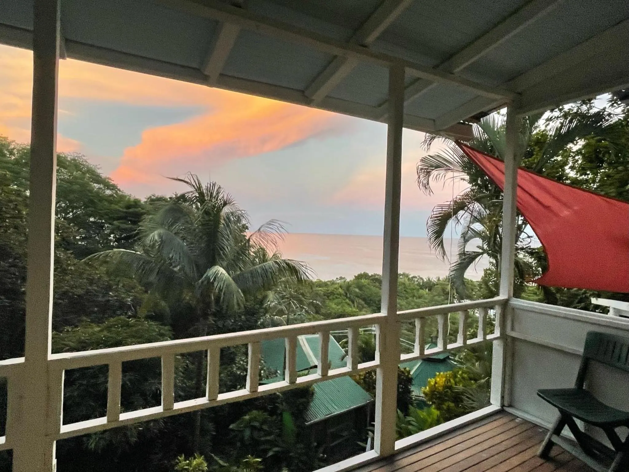 Terrasse avec vue sur la mer et la végétation luxuriante au coucher du soleil.
