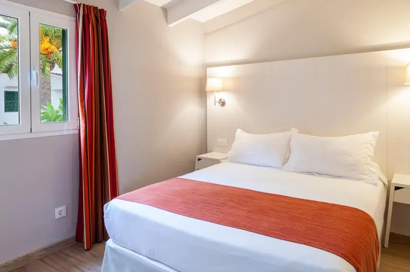 Une chambre lumineuse avec un grand lit et des rideaux colorés.