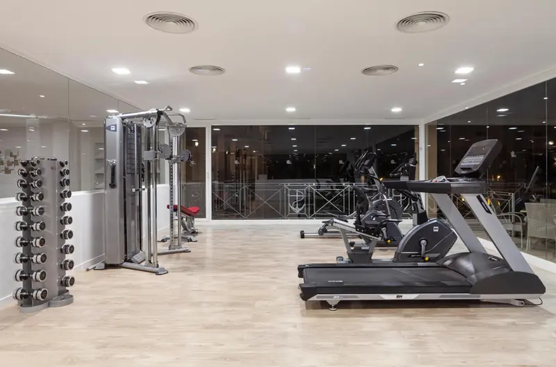 Une salle de sport lumineuse avec des équipements de musculation et des machines cardio.