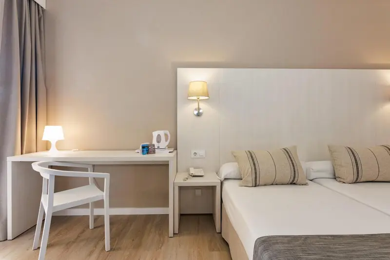 Une chambre lumineuse avec un bureau et un lit double.