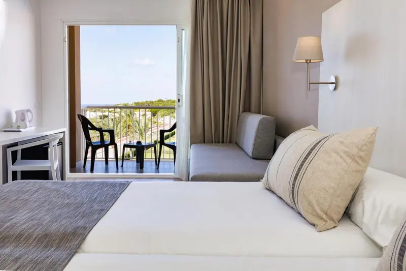 Une chambre lumineuse s'ouvre sur une terrasse avec vue sur la végétation.