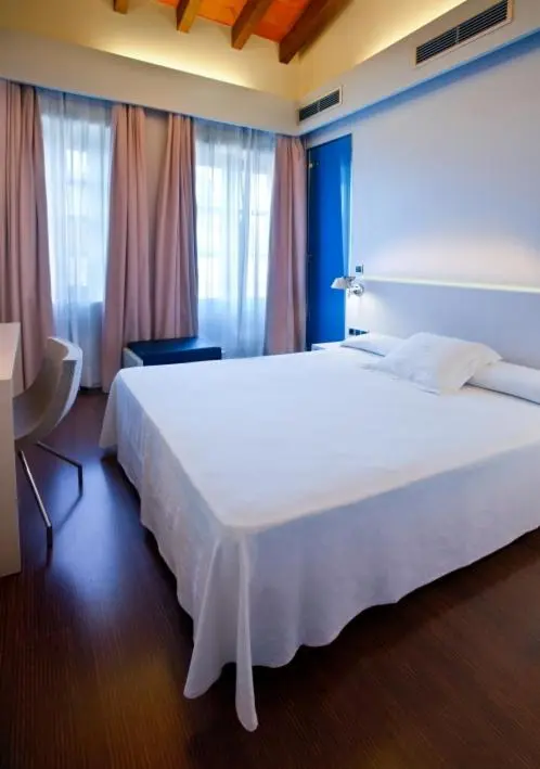 Une chambre lumineuse avec un grand lit recouvert d'une couverture blanche.