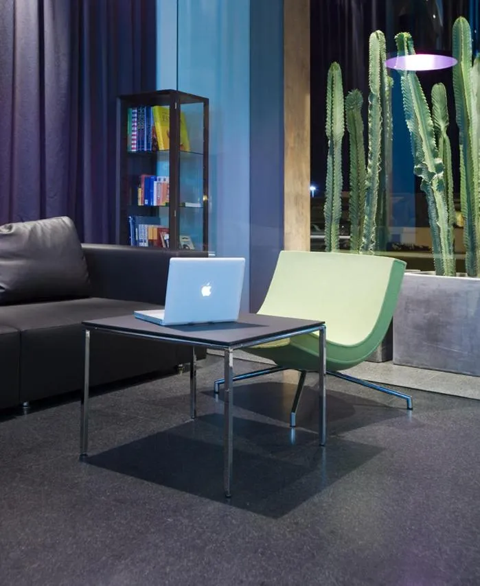 Un espace de détente intérieur avec un canapé noir, une table basse et des fauteuils.