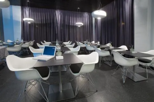 Une salle lumineuse avec des tables et des chaises blanches.