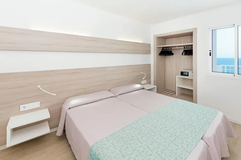 Une chambre lumineuse avec un lit double et un accès à une vue sur la mer.