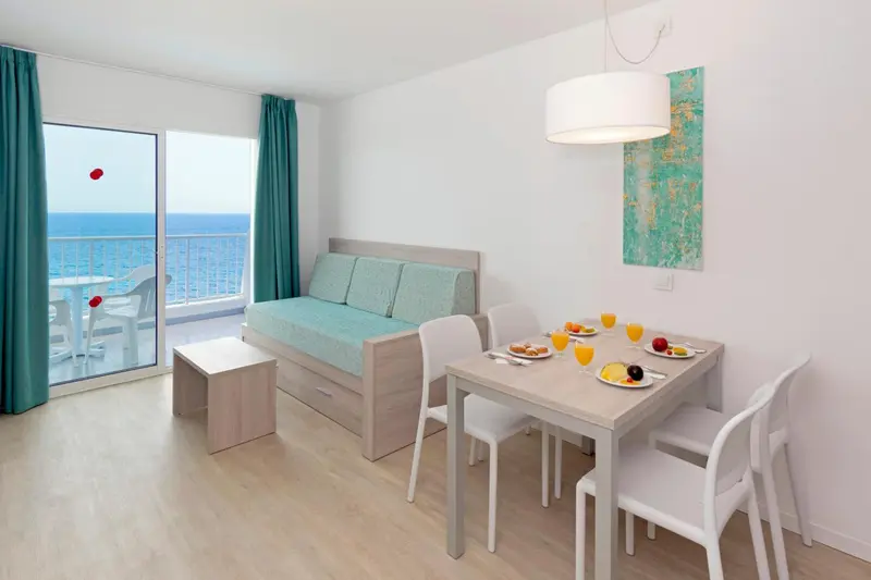 Espace de vie lumineux avec canapé, table et vue sur la mer.