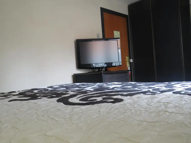 Une télévision murale est fixée au-dessus d'un meuble sombre dans une chambre.