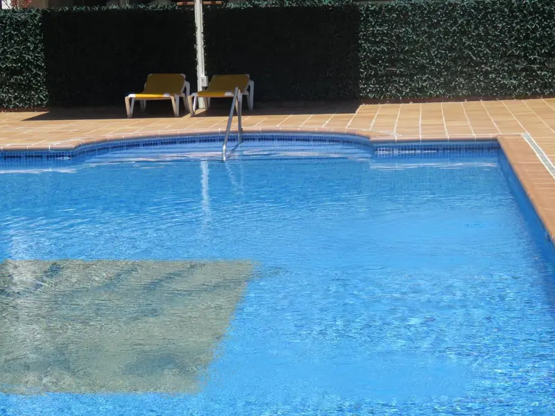 Une piscine rectangulaire avec des transats et un escalier d'accès.