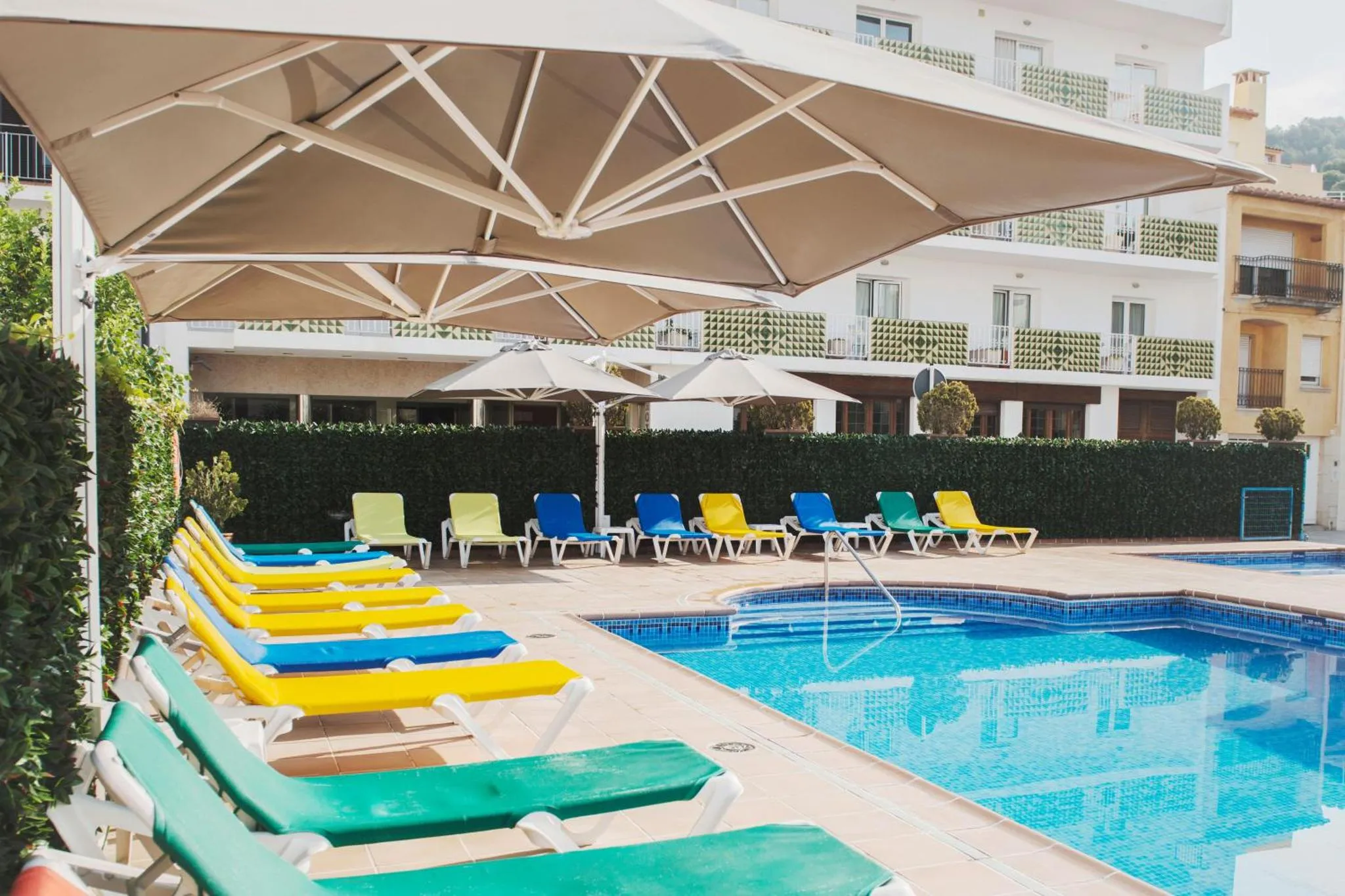 Transats colorés alignés au bord d'une piscine ensoleillée.