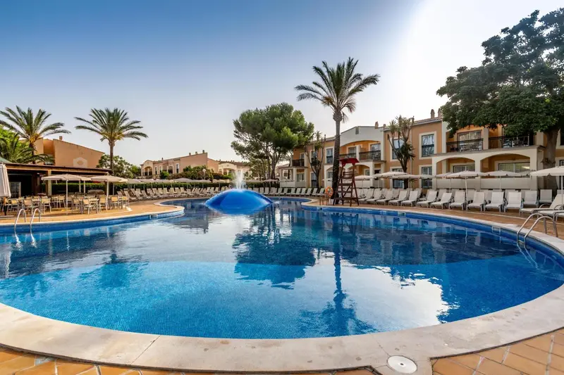 Piscine extérieure avec transats et végétation luxuriante.