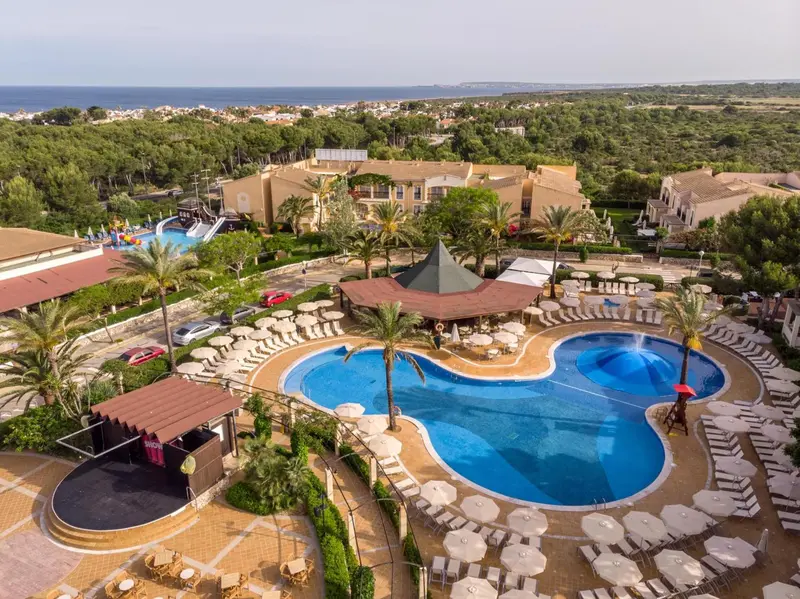 Vue aérienne d'un complexe hôtelier avec piscine et végétation luxuriante.