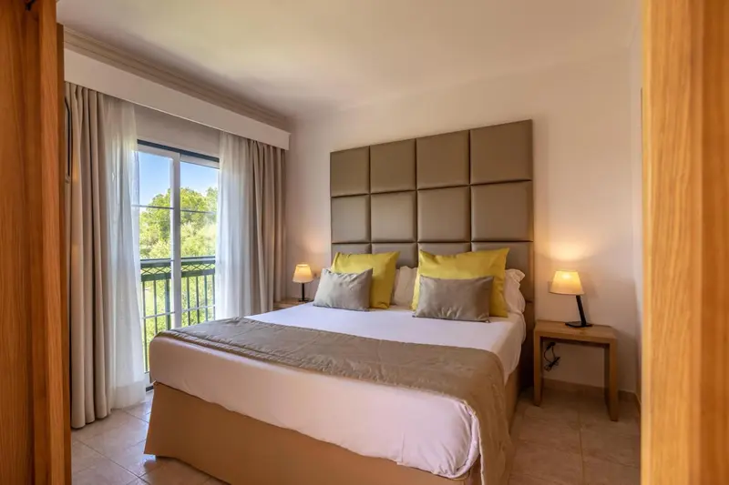 Chambre lumineuse avec un grand lit et des oreillers décoratifs.