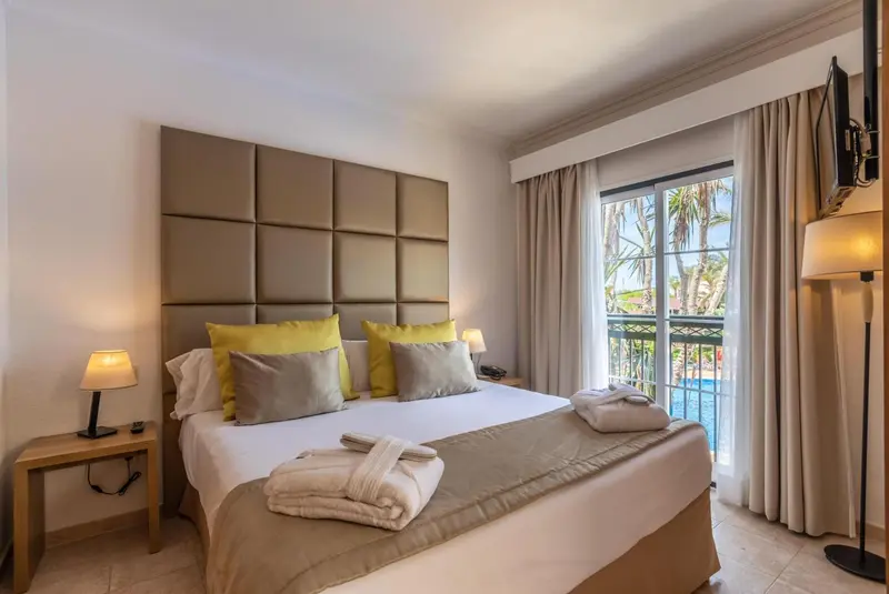 Une chambre lumineuse avec un grand lit et des oreillers décoratifs.