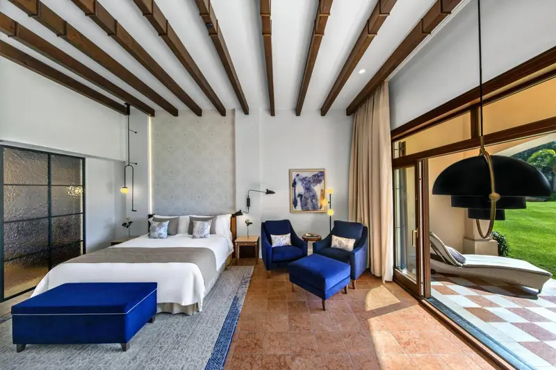 Une chambre lumineuse avec un lit king-size et un coin salon donnant sur une terrasse.