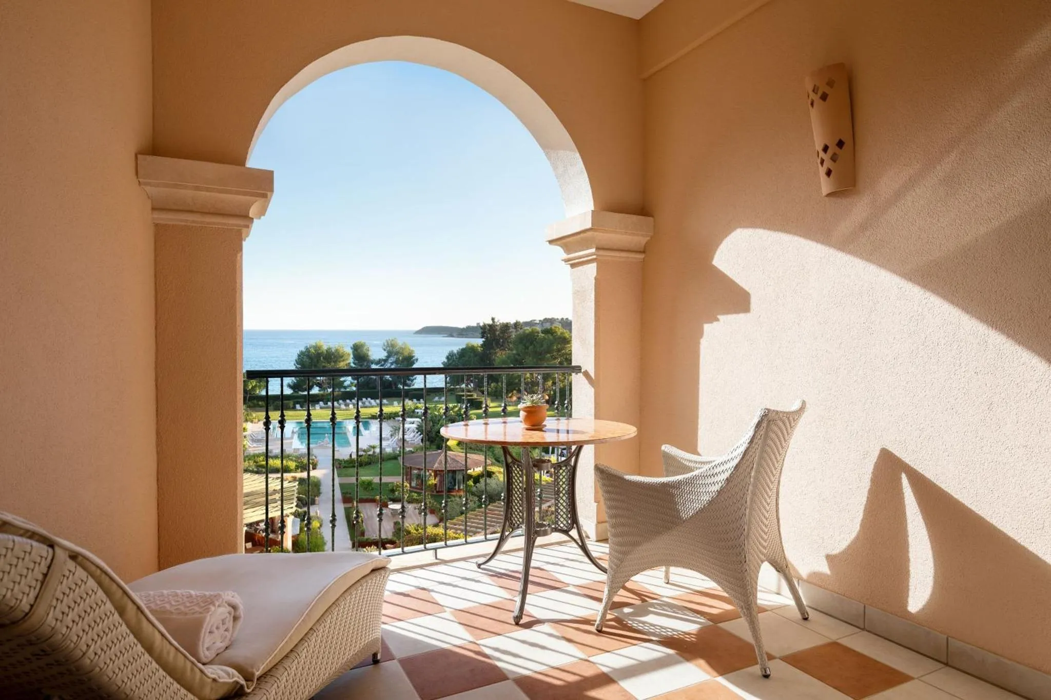 Une terrasse ensoleillée offre une vue sur la mer et la végétation.