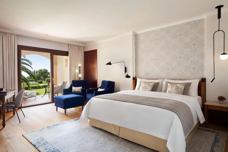 Une chambre lumineuse avec un grand lit et deux fauteuils bleus.