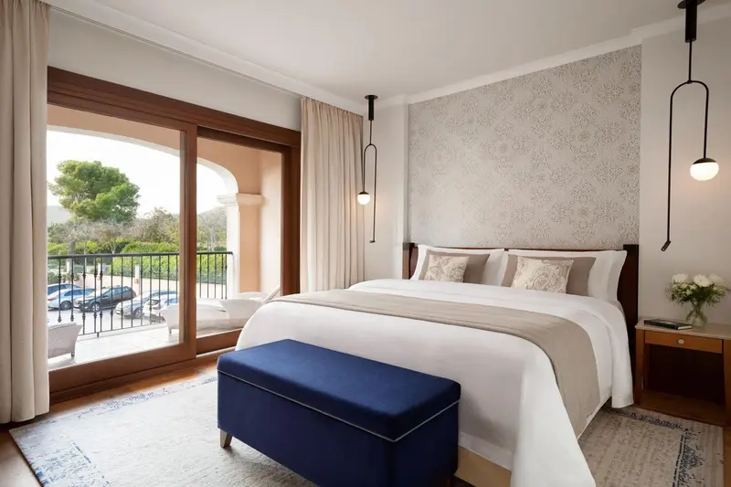 Chambre lumineuse avec un grand lit et un accès à un balcon.