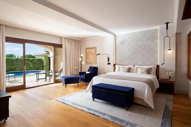Chambre lumineuse avec un lit king-size et un accès à une terrasse avec piscine.
