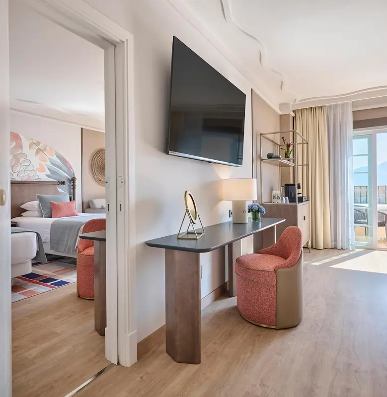 Une chambre lumineuse avec un bureau et un accès à un balcon.