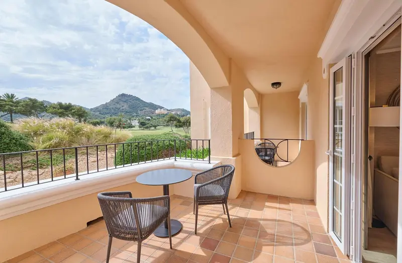 Terrasse avec mobilier de jardin et vue sur un paysage verdoyant.