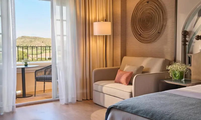 Un espace de détente avec un fauteuil et une vue sur un paysage ensoleillé.
