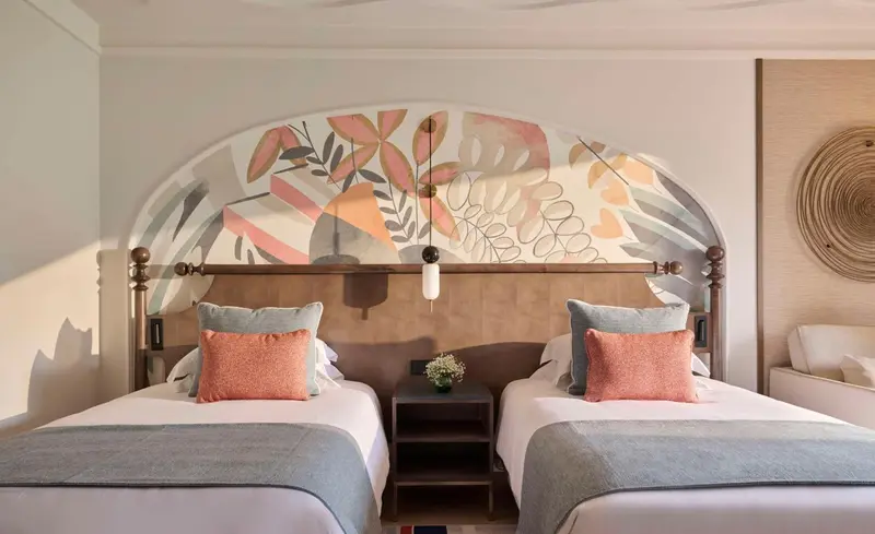 Chambre avec deux lits simples et une décoration murale florale.