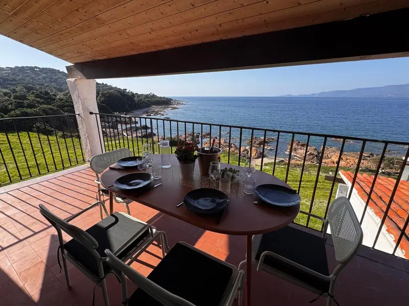 Une table est dressée sur une terrasse avec vue sur la mer.
