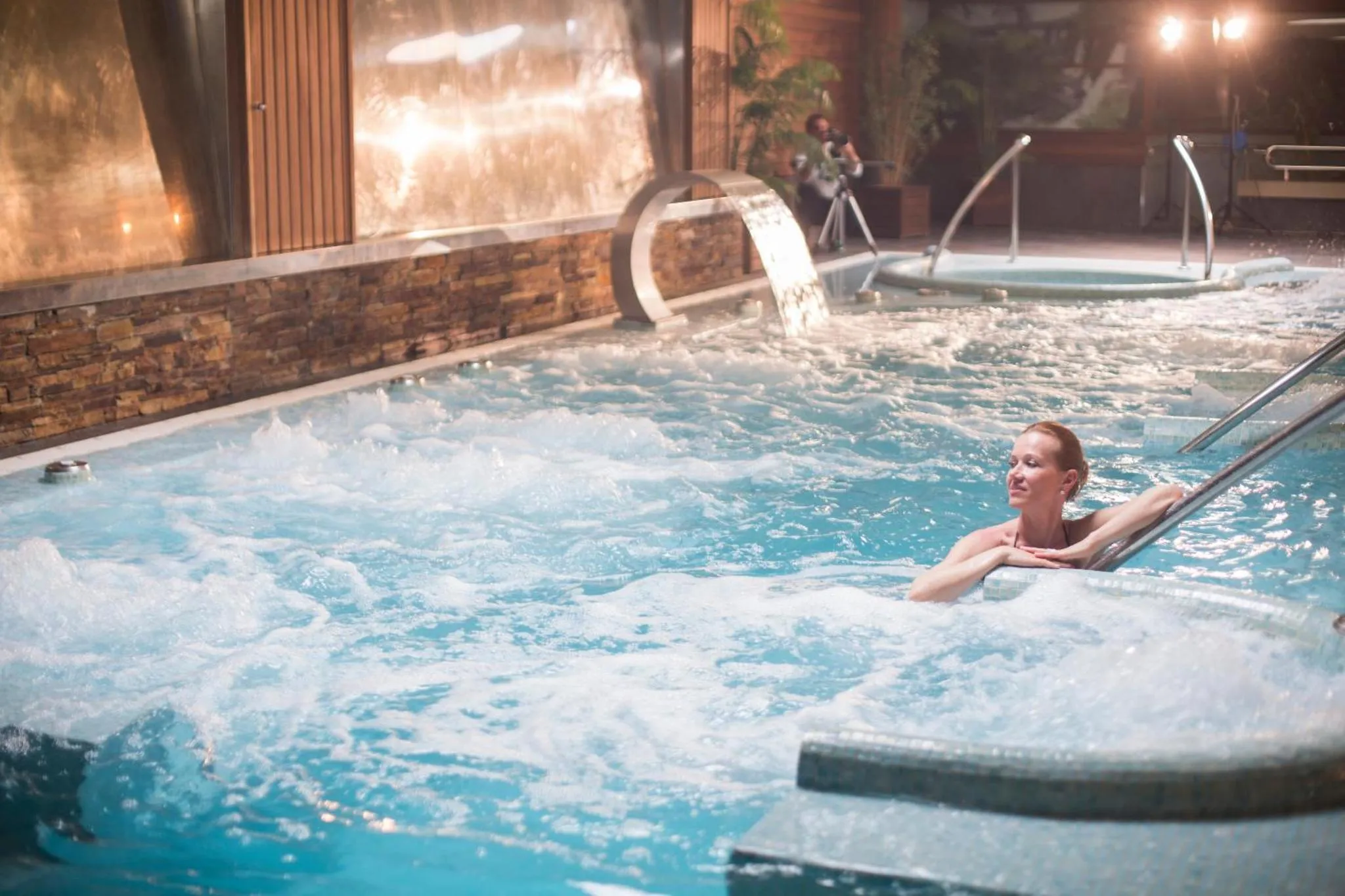 Une femme se détend dans une piscine intérieure avec des jets massants.