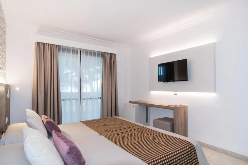 Une chambre lumineuse avec un lit double et un bureau.