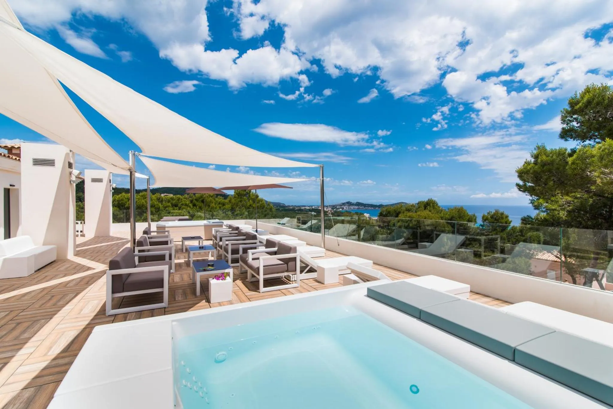 Terrasse aménagée avec salon de jardin et petite piscine offrant une vue sur la mer et les collines.