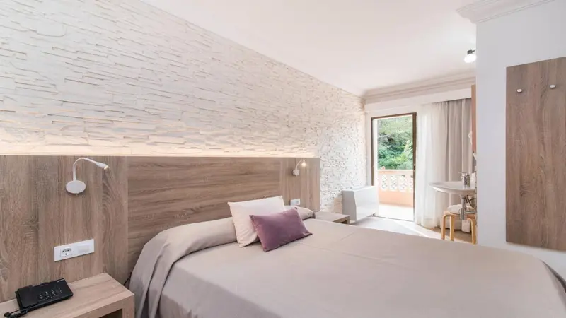 Une chambre lumineuse avec un grand lit et un mur texturé.