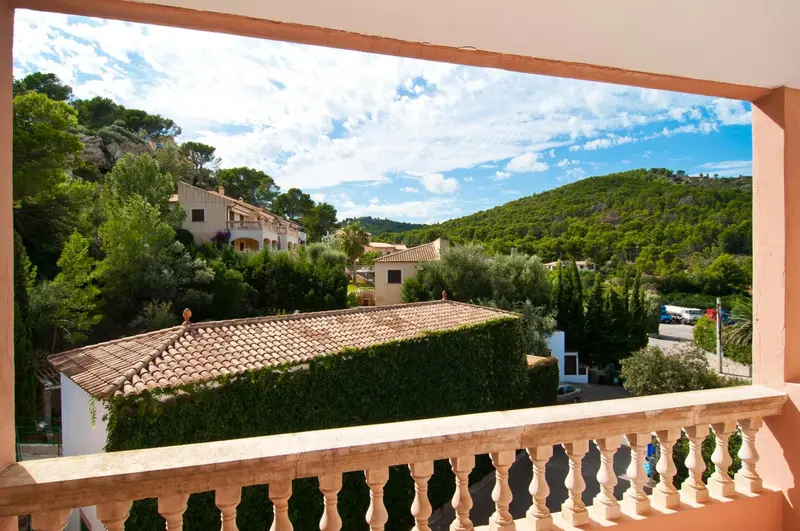 Vue sur un paysage verdoyant depuis un balcon avec balustrade.