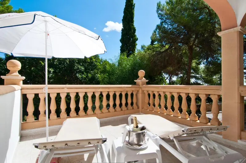 Transats blancs disposés sur une terrasse ensoleillée avec une balustrade.