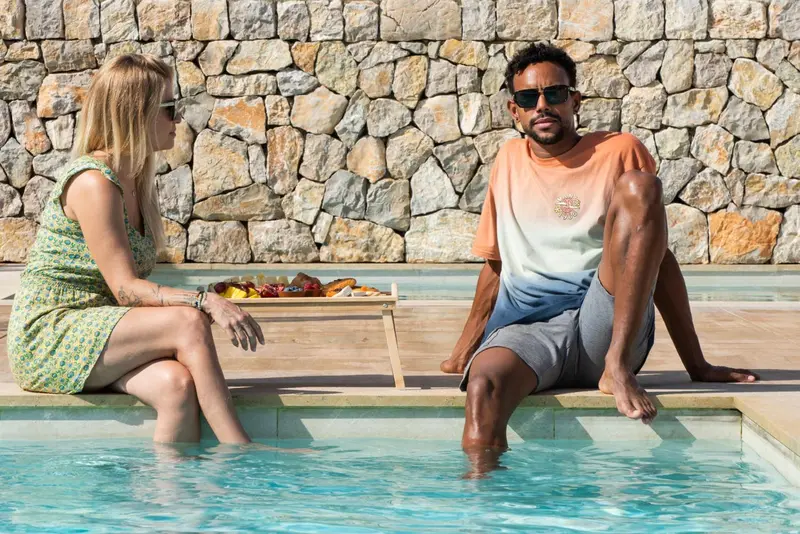 Deux personnes sont assises au bord d'une piscine avec un plateau de nourriture.
