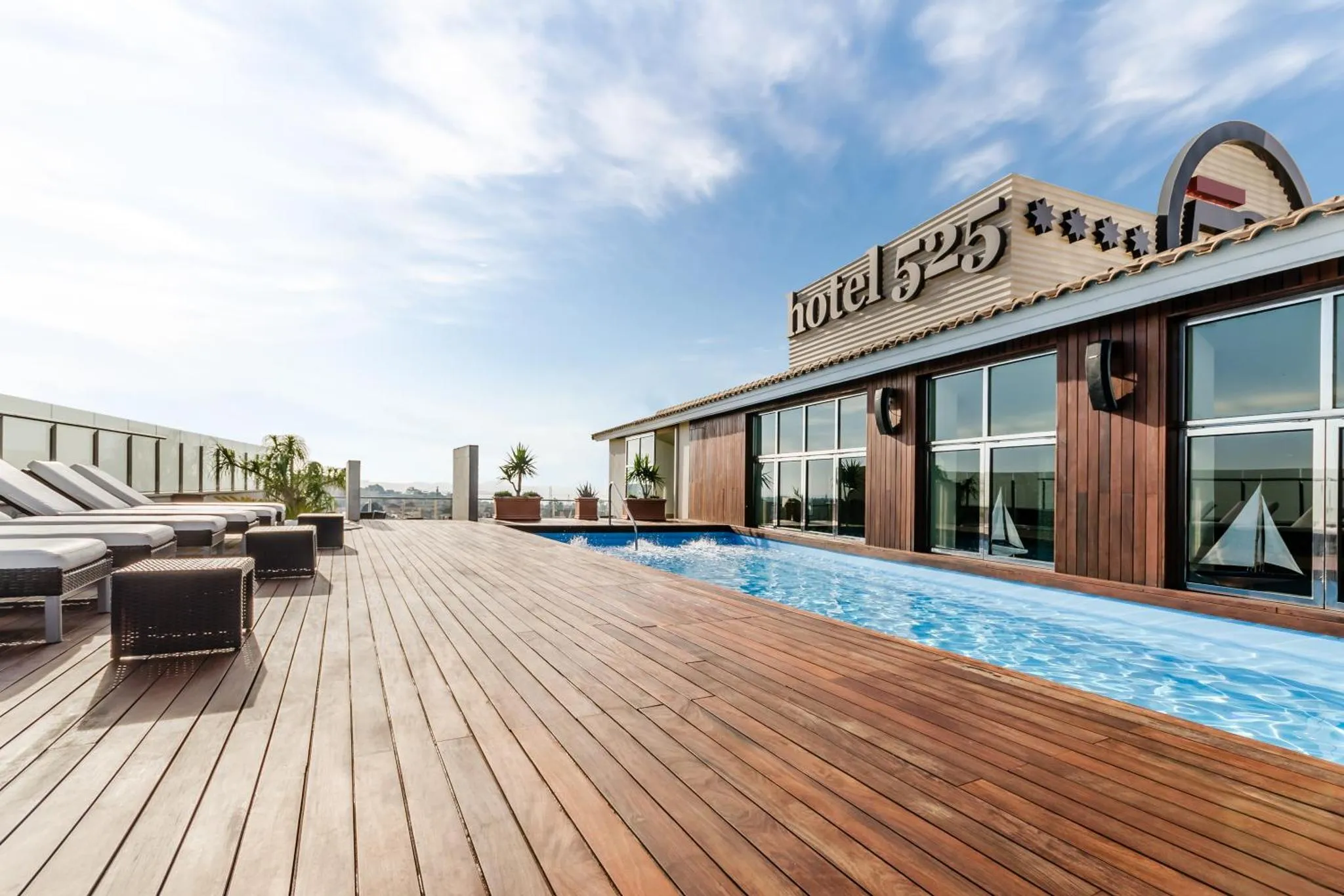 Terrasse avec piscine et chaises longues sur un toit.