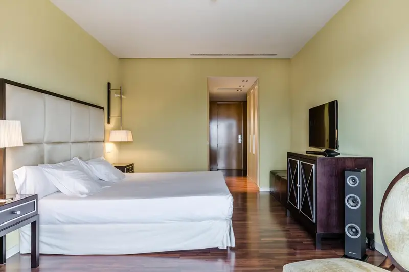 Une chambre lumineuse avec un grand lit et un meuble télévision.