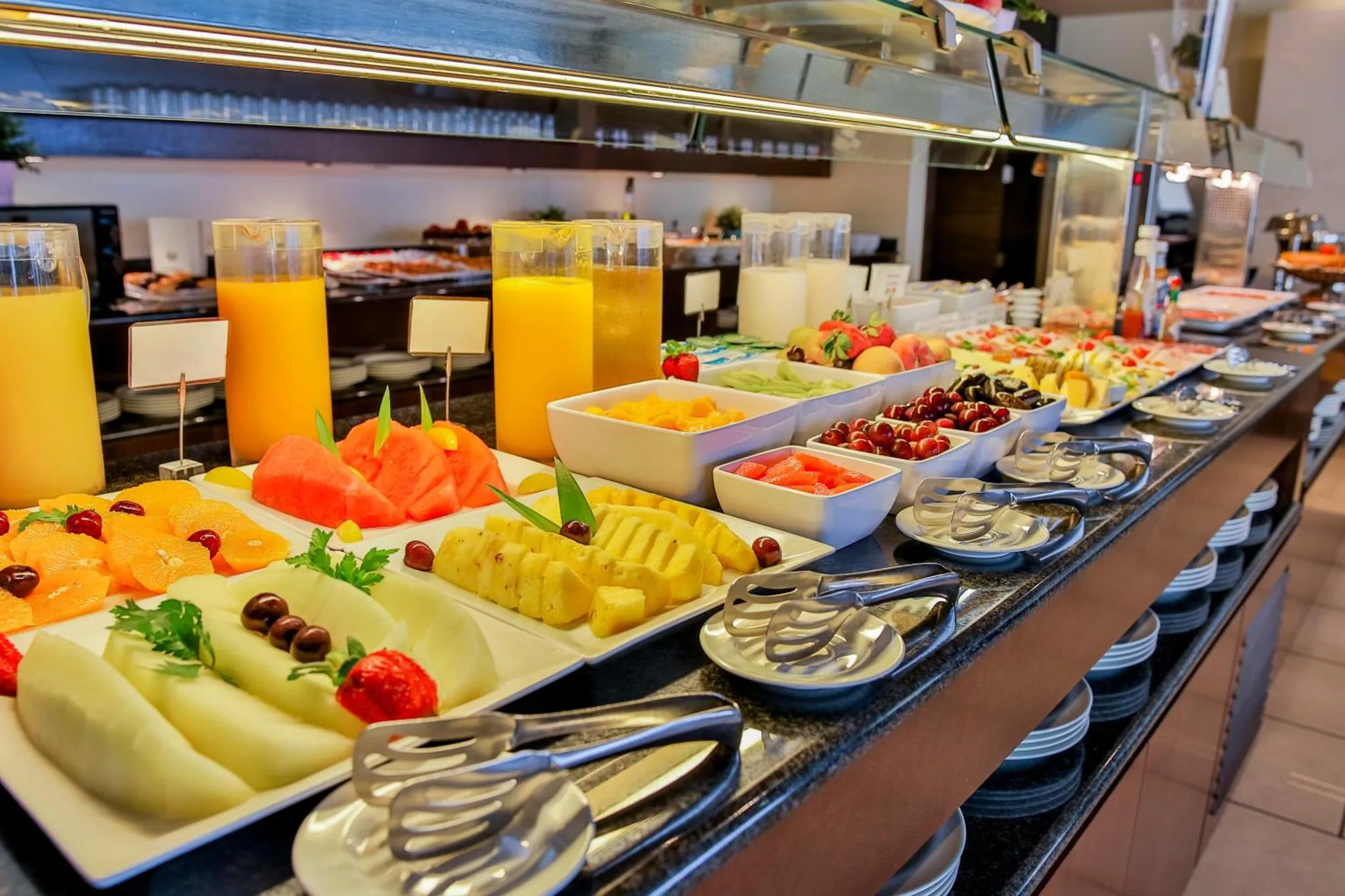 Un buffet propose une variété de fruits frais et de jus.