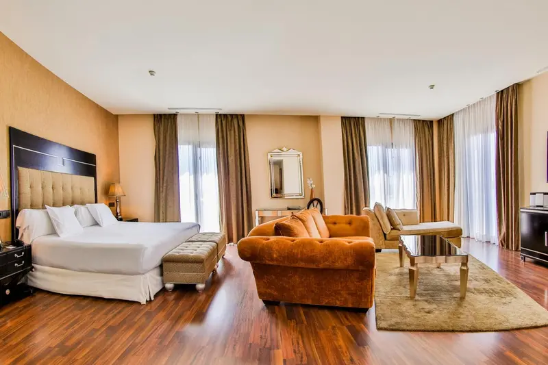 Une chambre spacieuse avec un grand lit et un coin salon confortable.