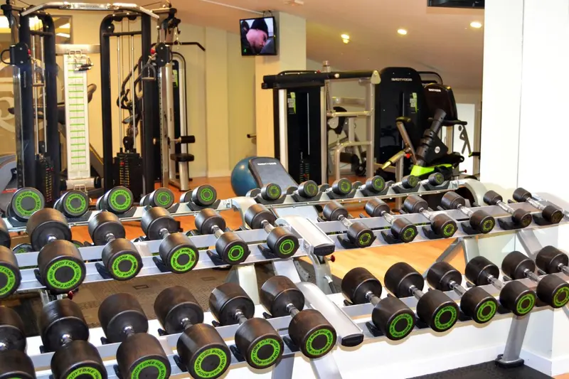 Une salle de sport lumineuse avec des rangées d'haltères et des machines de musculation.