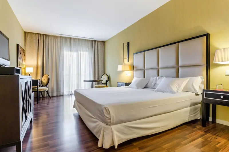 Une chambre lumineuse avec un grand lit et un coin salon.