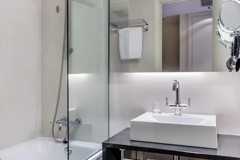 Une salle de bain moderne avec douche à l'italienne et vasque blanche.