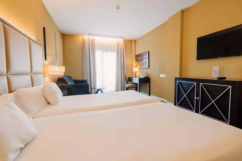 Une chambre lumineuse avec un grand lit et un bureau.