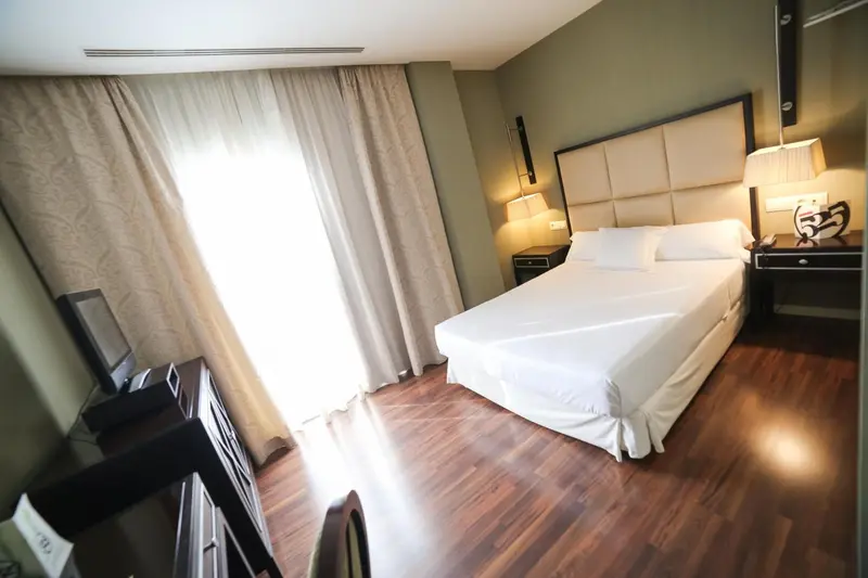 Une chambre lumineuse avec un grand lit et des rideaux clairs.