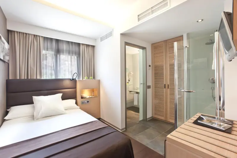 Chambre moderne avec un grand lit et une salle de bain vitrée.