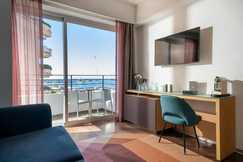 Une chambre lumineuse s'ouvre sur un balcon avec vue sur la mer.