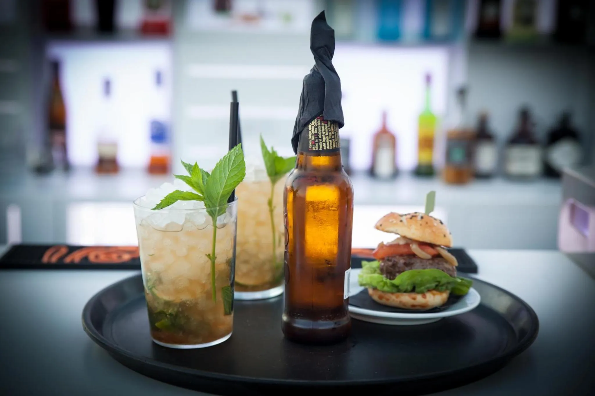 Un plateau de service présente des boissons et un hamburger.