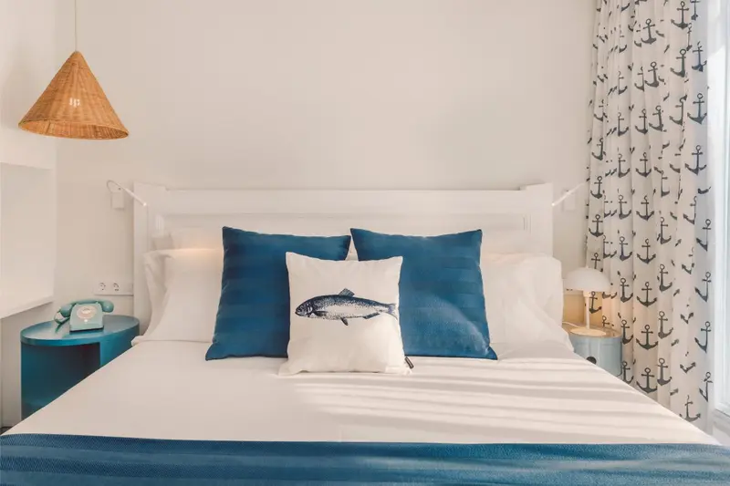 Une chambre lumineuse avec un lit recouvert de coussins bleus et blancs.