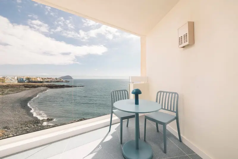 Terrasse avec mobilier bleu donnant sur la mer et le rivage.